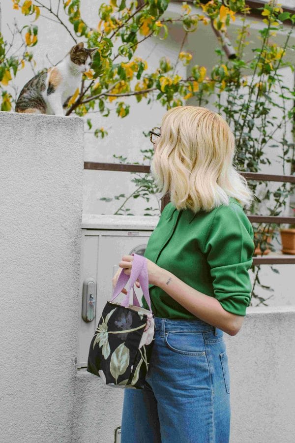 femeie ține o geantă textilă care se leagă cu șnur.